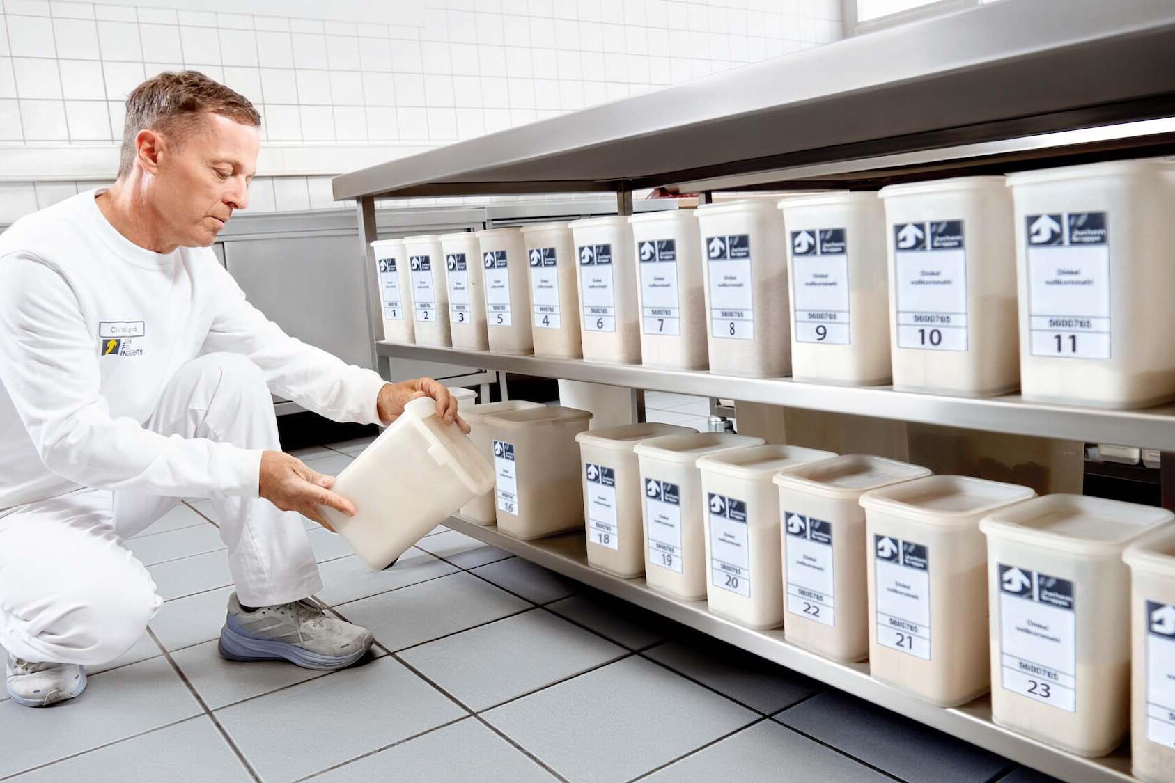 Mitarbeiter der JUCHEM GROUP kontrolliert und organisiert Rohstoffe in beschrifteten Behältern im Produktions- und Entwicklungsbereich.