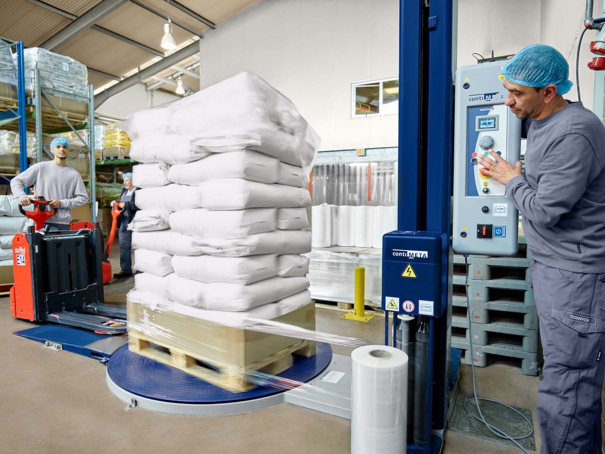 Mitarbeiter der JUCHEM GROUP sichern und verpacken Rohstoffsäcke auf Paletten im Produktions- und Lagerbereich.